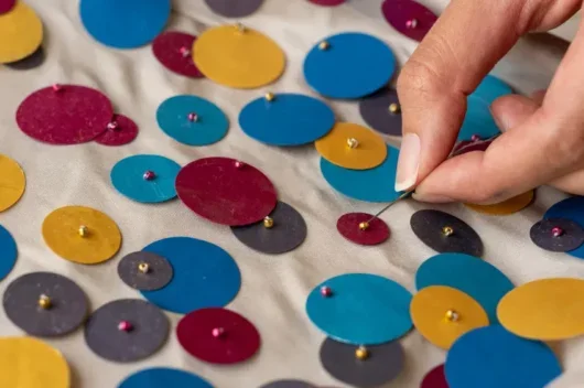 Close up of hand sewing sequins