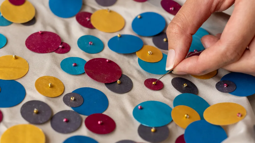 Close up of hand sewing sequins