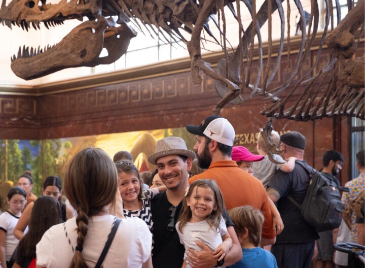 Family smiles for portrait in front of dinosaur bones